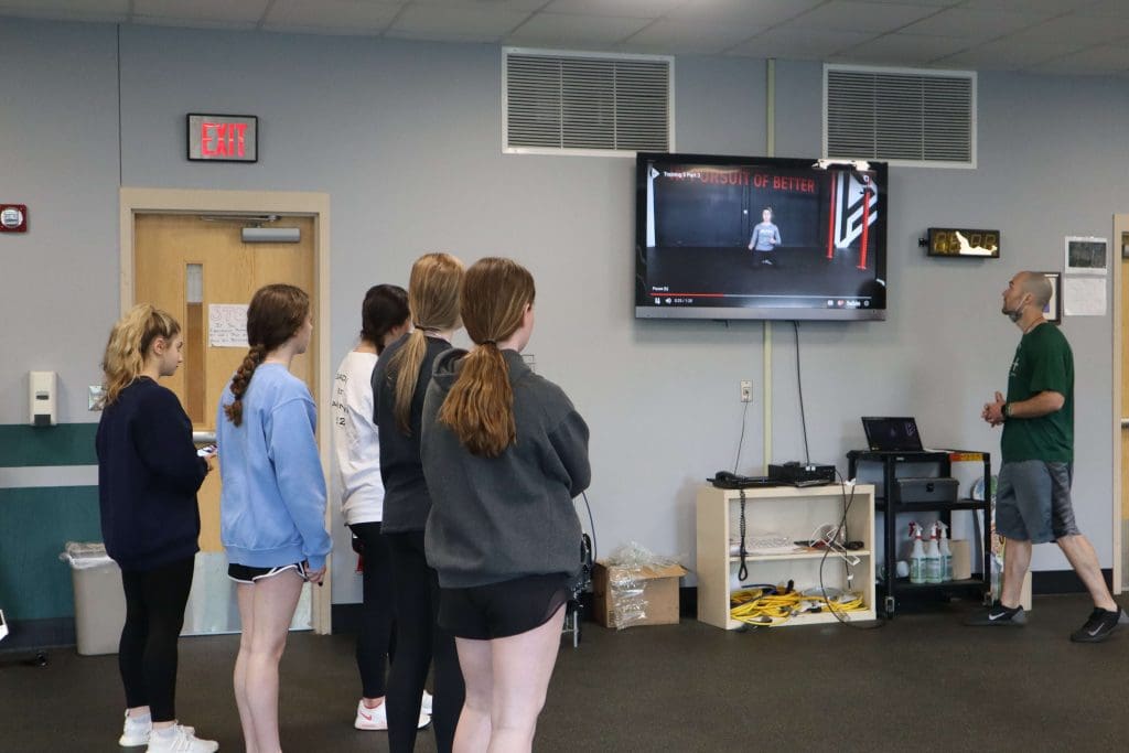 Students watch a PLT4M instructional video in PE class.