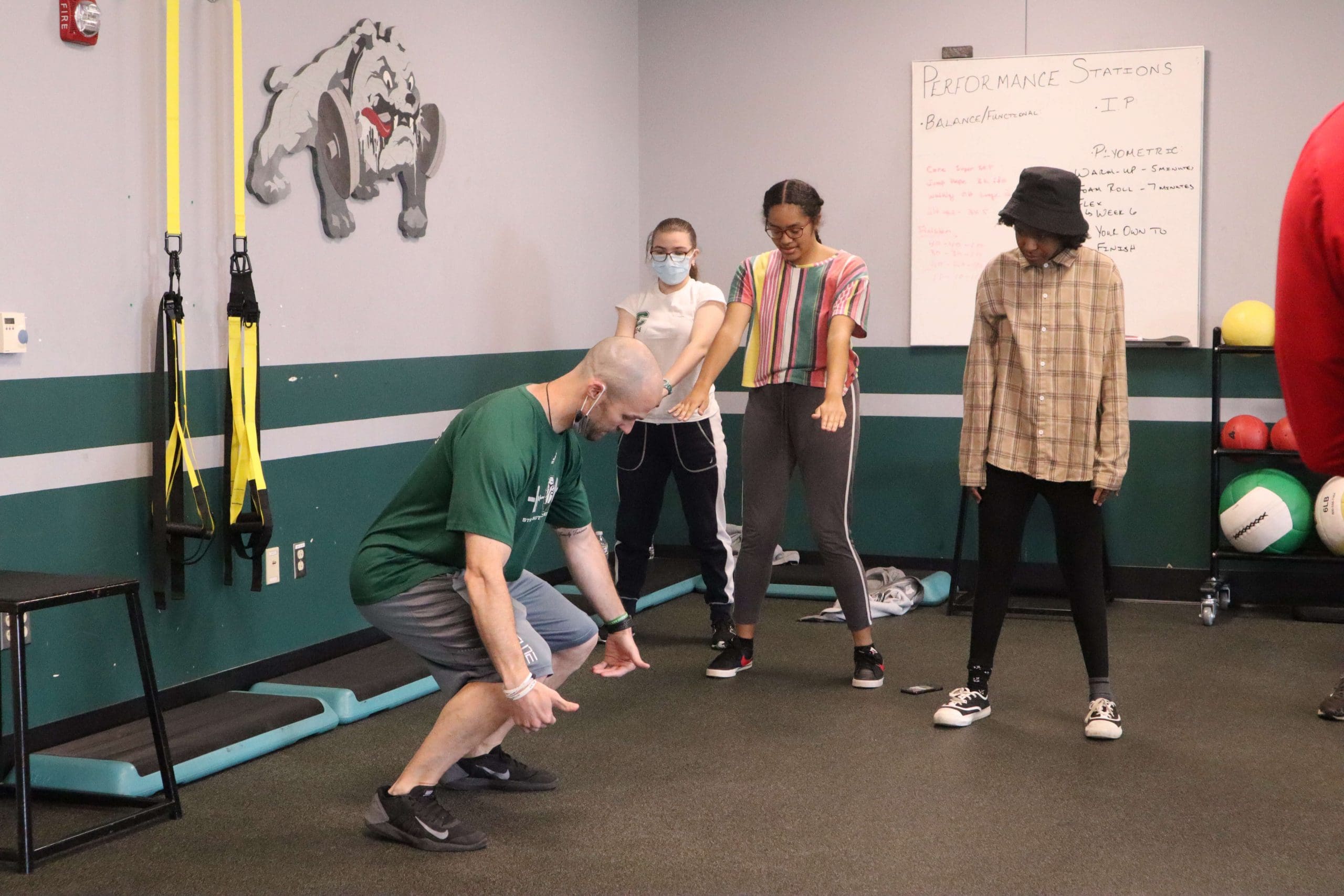 A teacher explains the points of performance of an air squat during physical education class.
