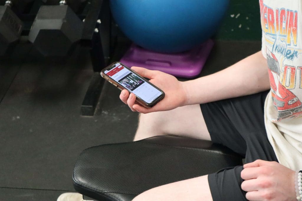 A student checks the PLT4M app during a workout.