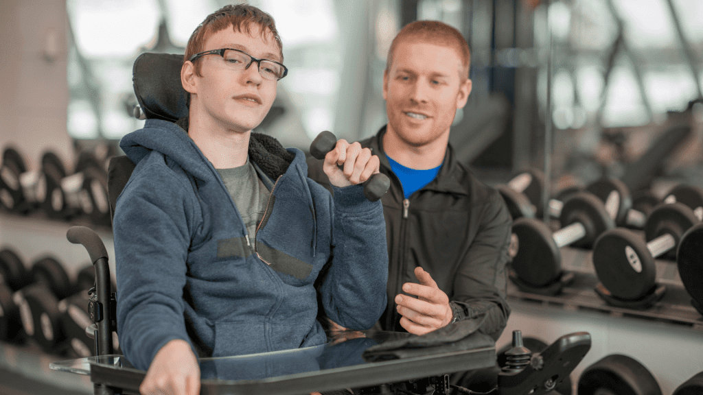 A fitness instructor works with a student in a wheel chair.