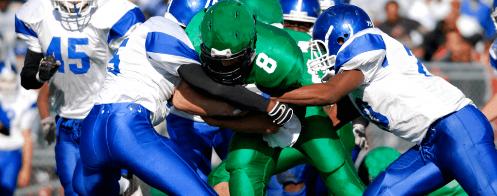 A football player is tackled while carrying the ball.