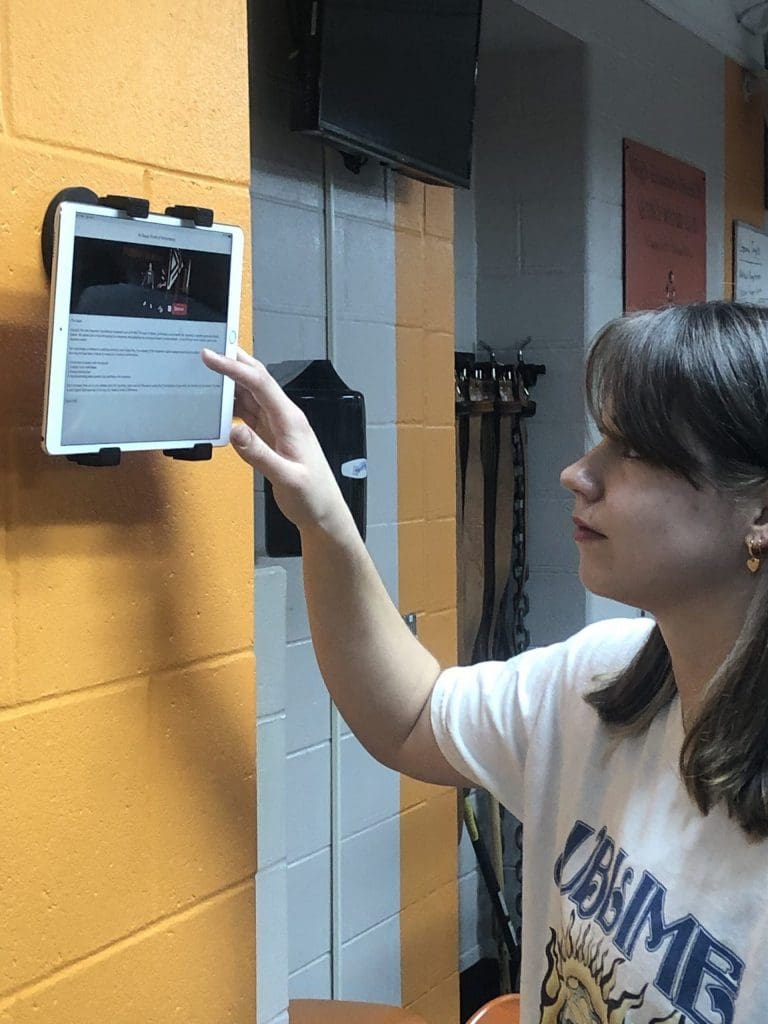 A student logs a PLT4M workout using an Ipad in physical education class.