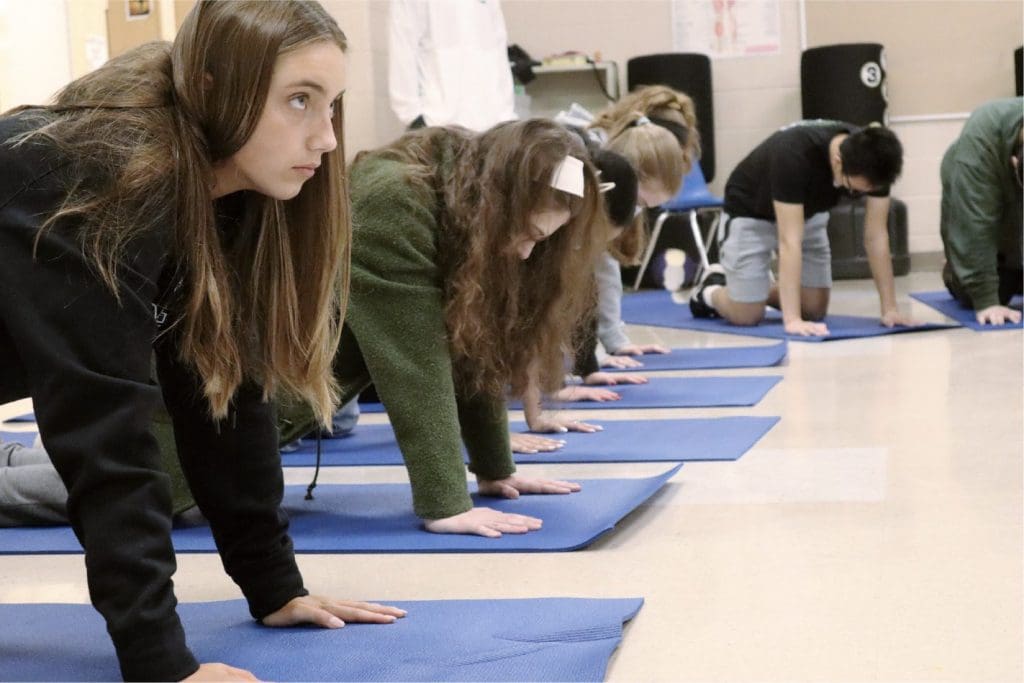 Students do yoga in a physical education class.