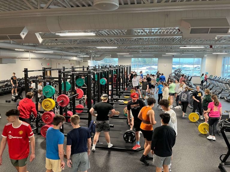 Bird's eye view of inside the Plymouth High School weight room with students training.