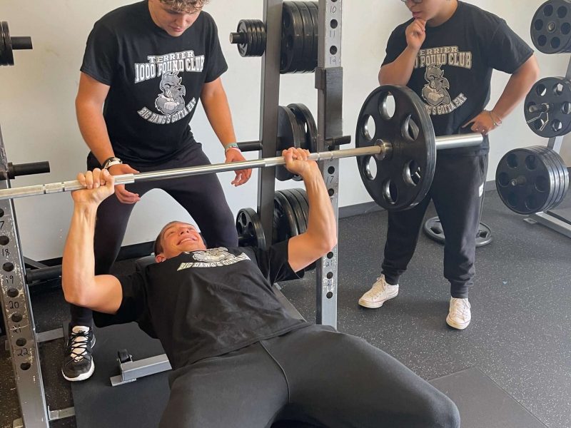 Carbondale student performs bench press with a spotter and onlooker.